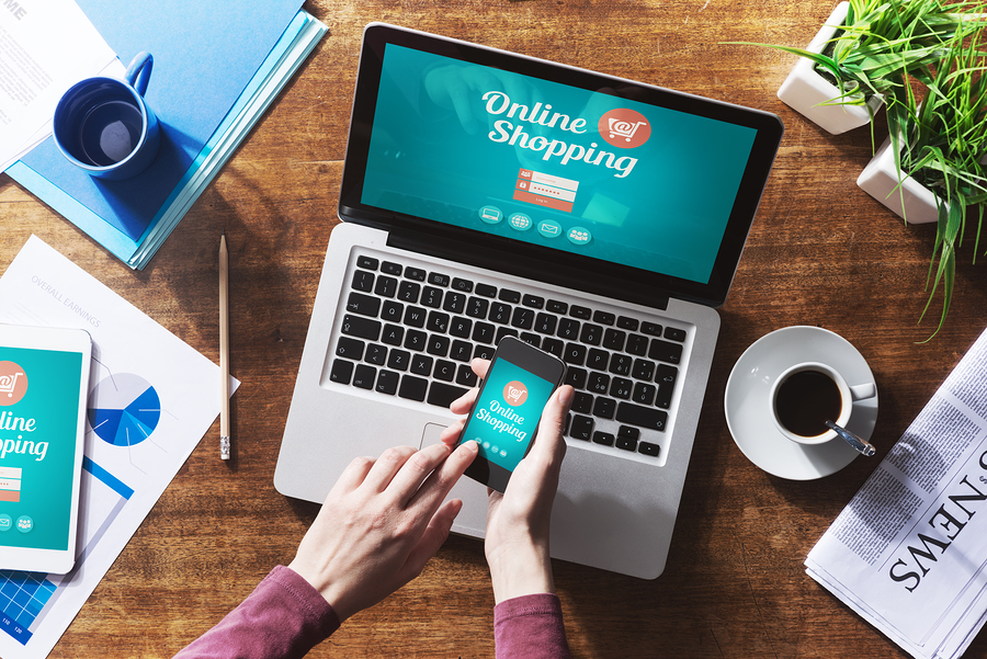 Online Mobile Shopping holding mobile phone and on laptop