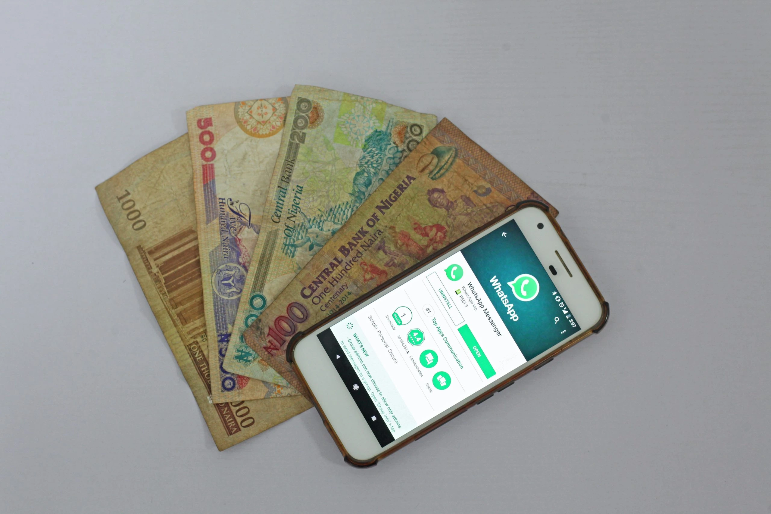 Whatsapp app on mobile phone next to Nigerian Naira money