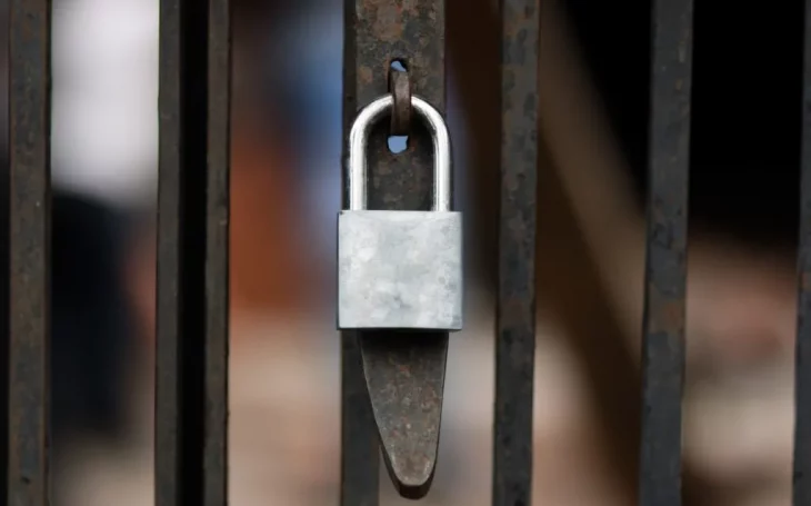 silver lock attached to rusty fence